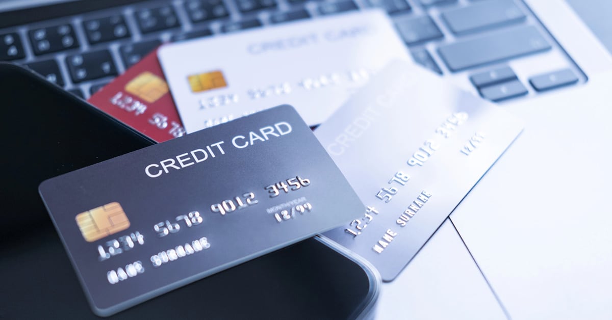 A close-up of multiple credit cards placed on a laptop keyboard, symbolizing digital transactions and online payment processing. The cards have embossed numbers and chip technology, emphasizing secure financial transactions.